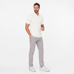 Man wearing a white polo shirt and gray pants on a white background