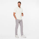 Man wearing a white polo shirt and gray pants on a white background