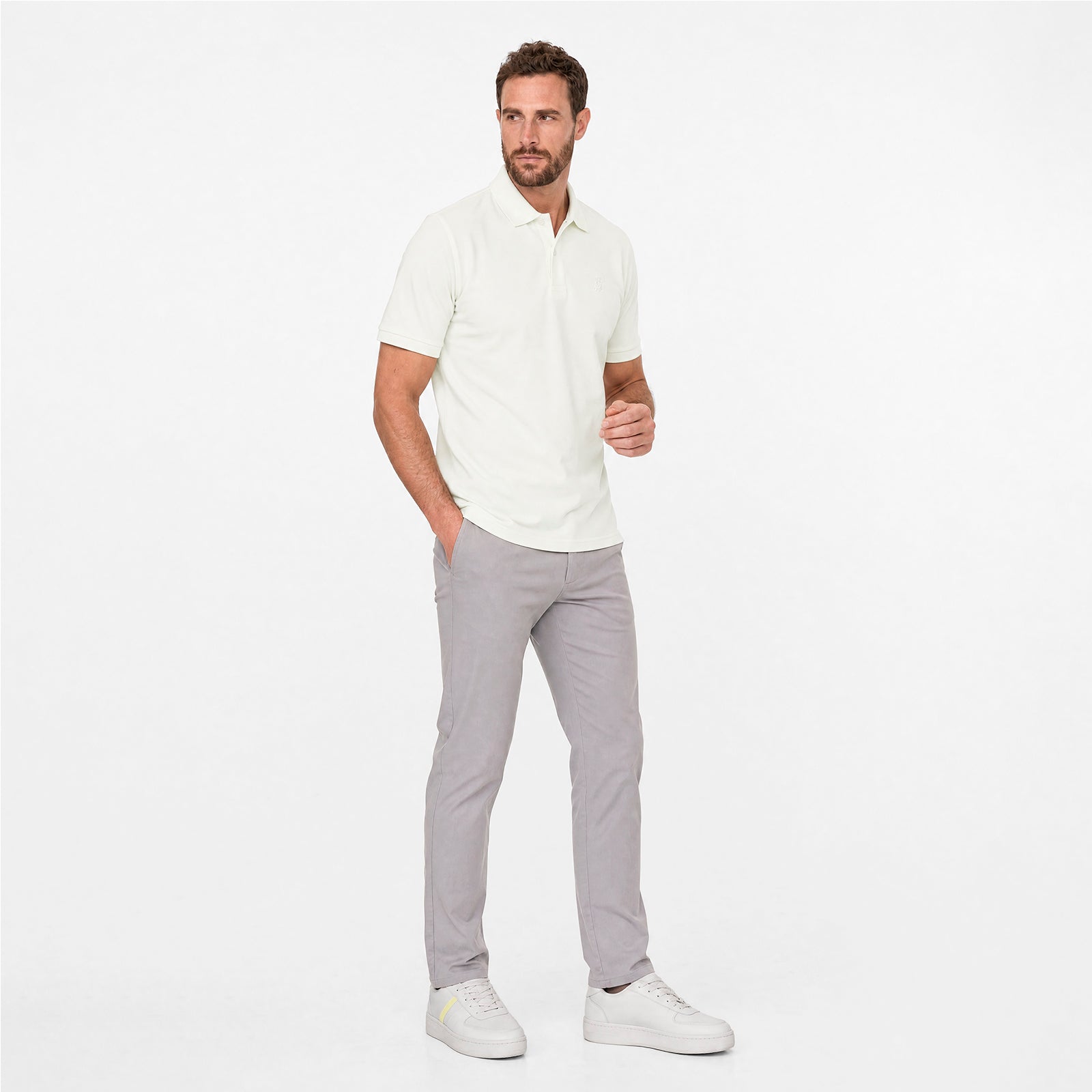 Man wearing a white polo shirt and gray pants on a white background