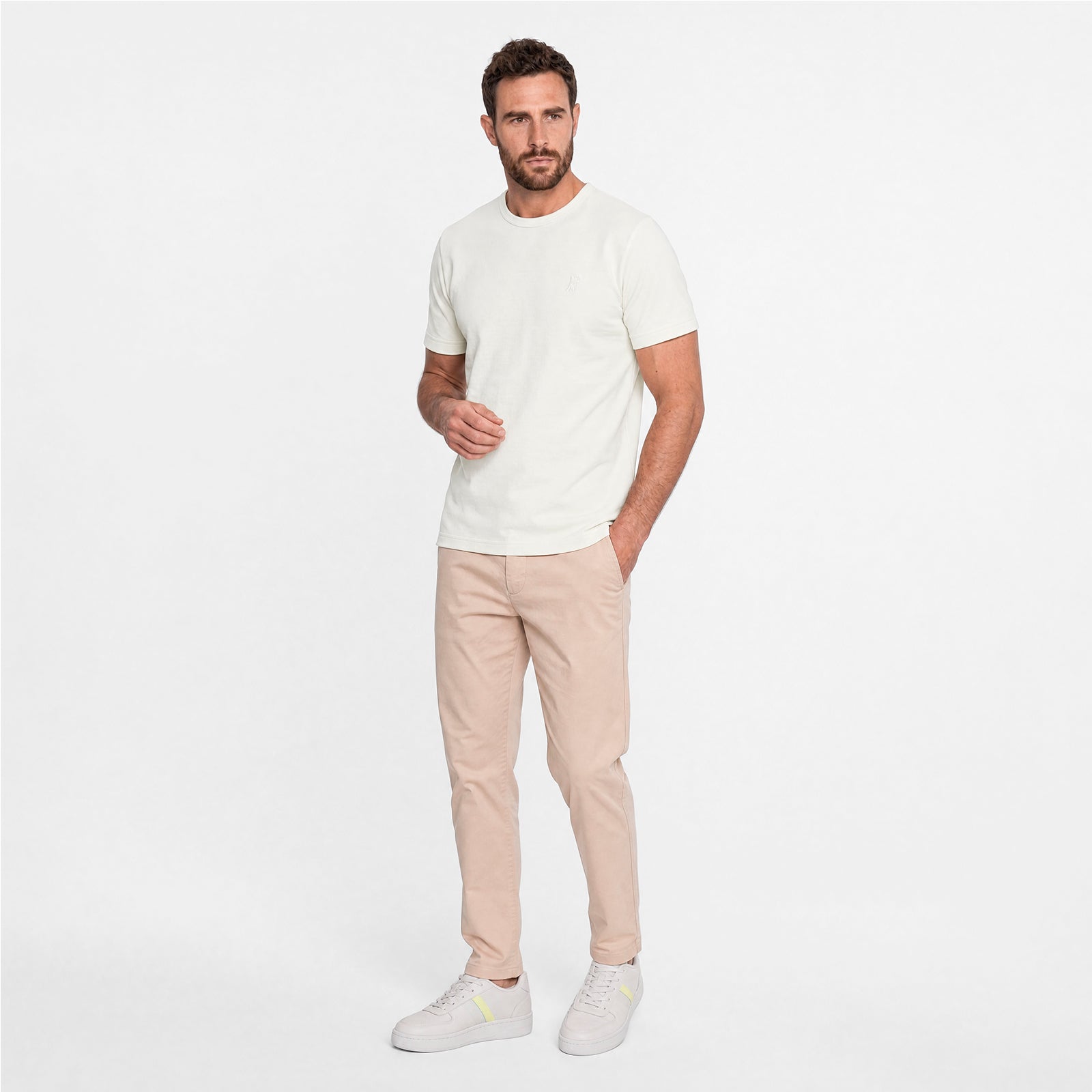 Man wearing a white t-shirt and beige pants on a white background