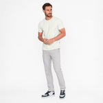 Man wearing a white t-shirt and gray pants on a white background