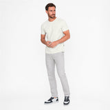 Man wearing a white t-shirt and gray pants on a white background