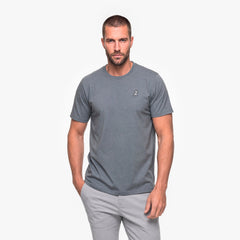 Man wearing a gray t-shirt with a small logo on a white background