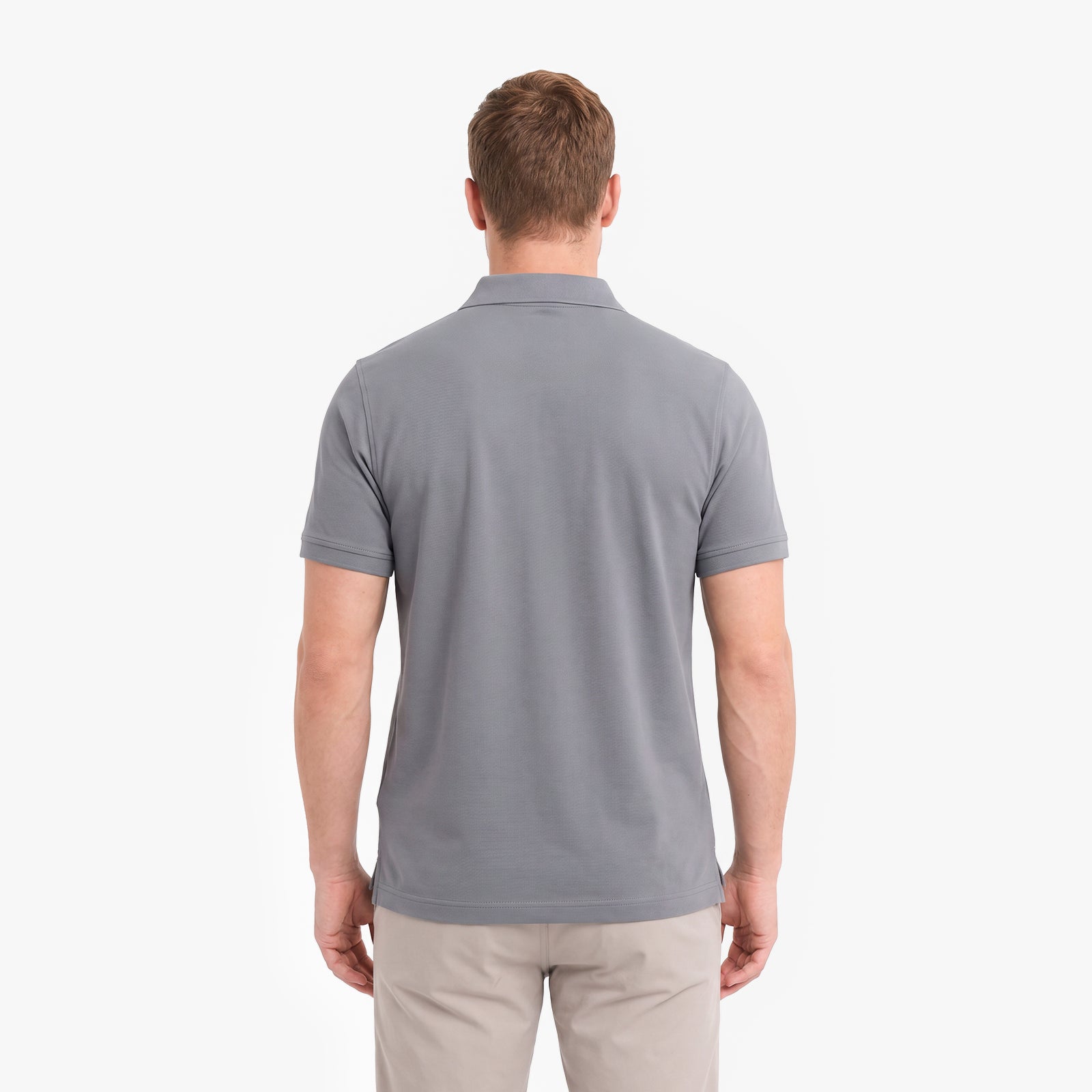 A man viewed from the back wearing a short-sleeve gray polo shirt and beige trousers