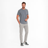 Man wearing a gray t-shirt and light gray pants on a white background