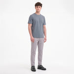 A man modeling a short-sleeve crewneck t-shirt in slate gray, paired with light gray trousers
