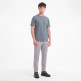 A man modeling a short-sleeve crewneck t-shirt in slate gray, paired with light gray trousers