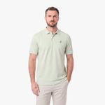 A man wearing a light sage green polo shirt with a small embroidered logo on the left chest