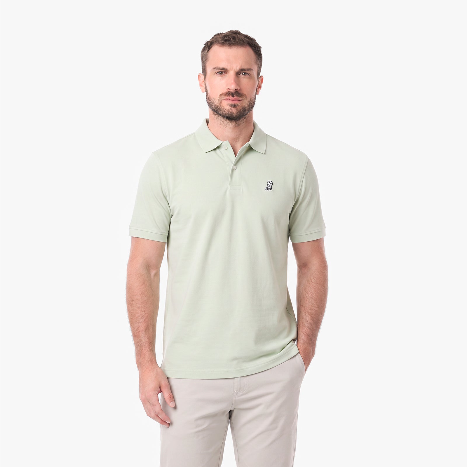 A man wearing a light sage green polo shirt with a small embroidered logo on the left chest
