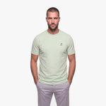 Man wearing a light green t-shirt with a white logo on a white background