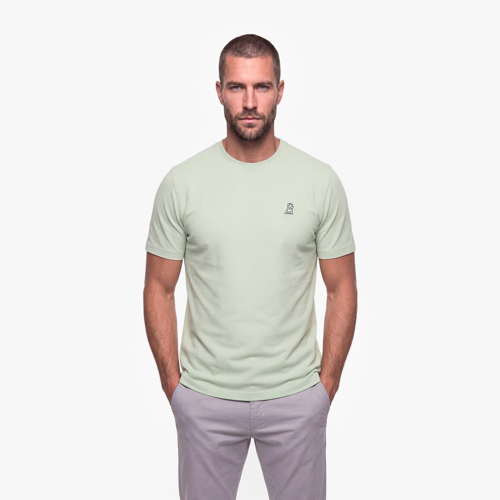 Man wearing a light green t-shirt with a white logo on a white background