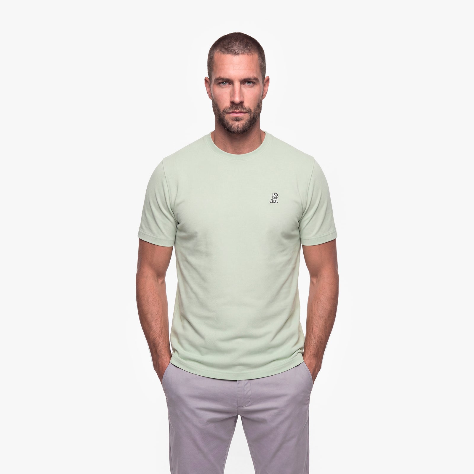 Man wearing a light green t-shirt with a small logo on a white background