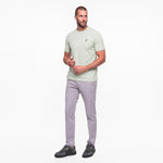 Man wearing a light green t-shirt and gray pants on a white background
