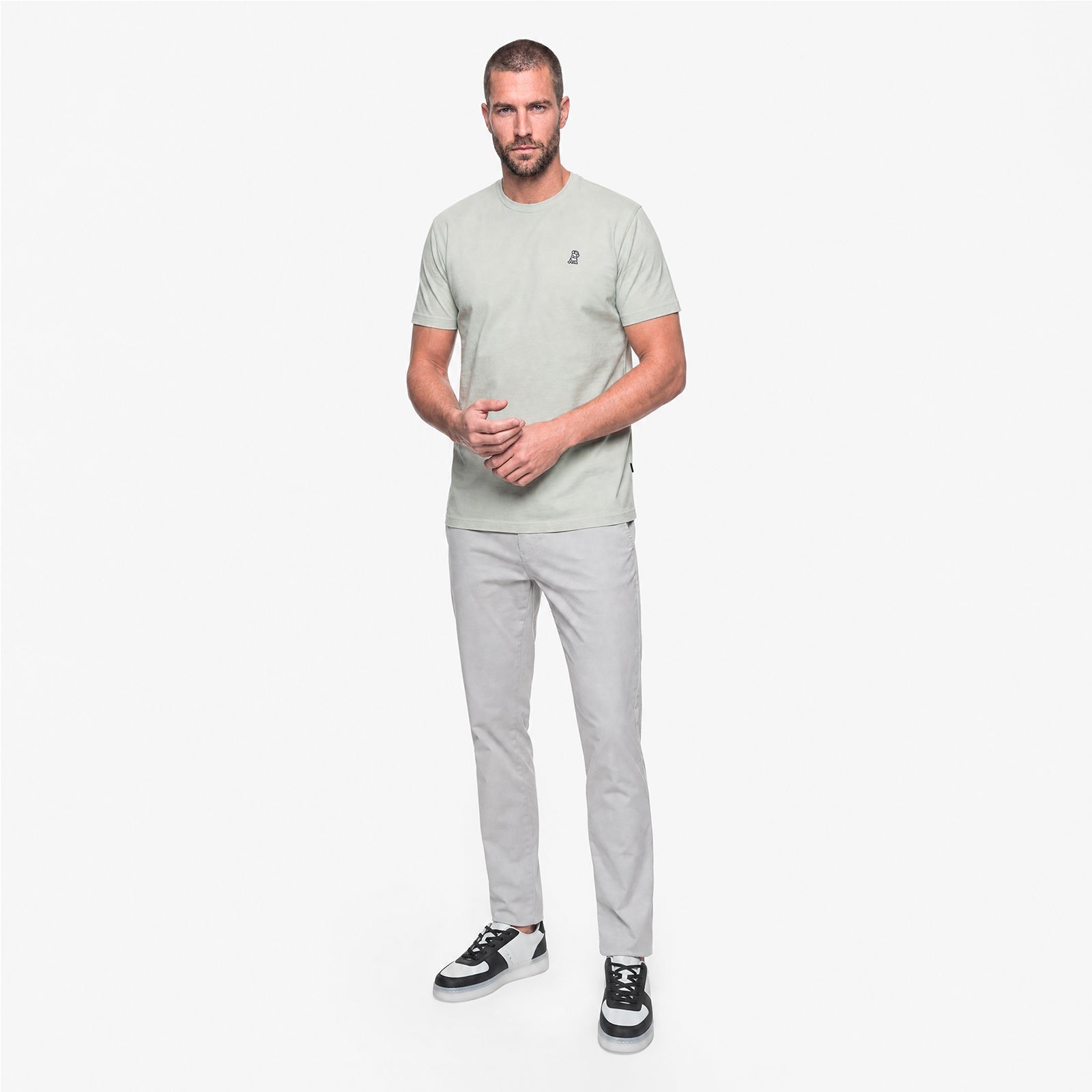 Man wearing a light gray t-shirt and pants on a white background