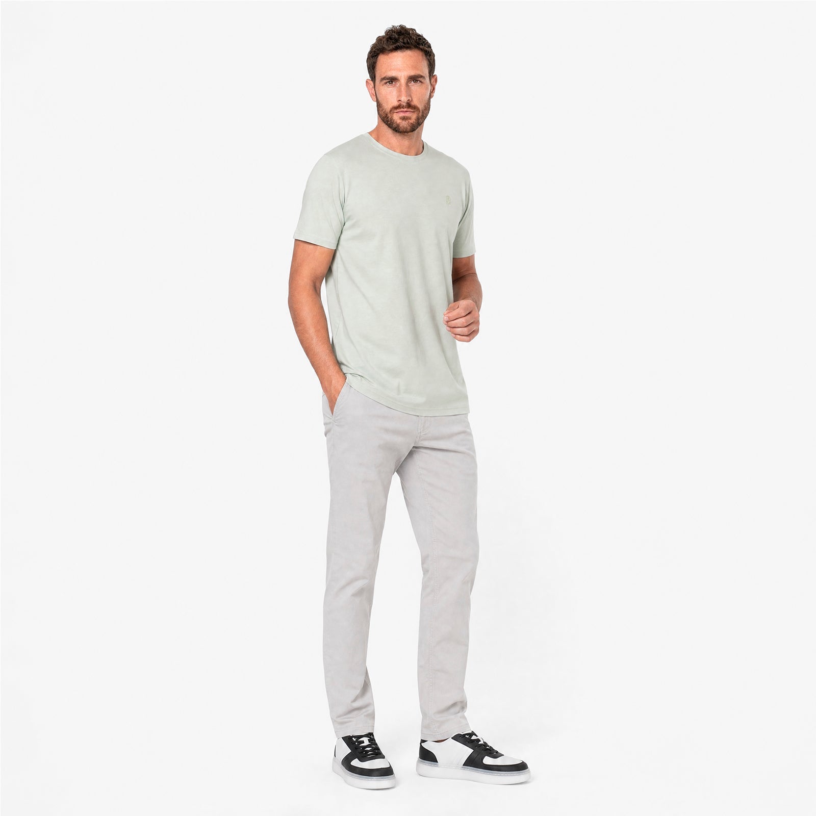 Man wearing a light gray t-shirt and pants on a white background