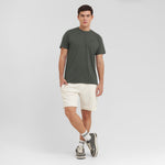 Man wearing a green t-shirt and beige shorts on a white background