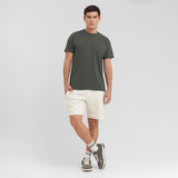 Man wearing a green t-shirt and beige shorts on a white background