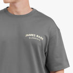 Close-up of the "JAMES BARK ELEMENTS" logo in off-white text on the chest of the gray t-shirt