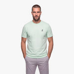 Man wearing a light green t-shirt with a white embroidered logo on a white background