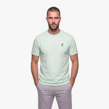 Man wearing a light green t-shirt with a white embroidered logo on a white background