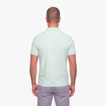 Man wearing a light green polo shirt on a white background