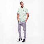 Man wearing a light green polo shirt and gray pants on a white background