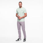 Man wearing a light green t-shirt and gray pants on a white background