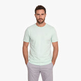 Man wearing a light green t-shirt and gray pants on a white background