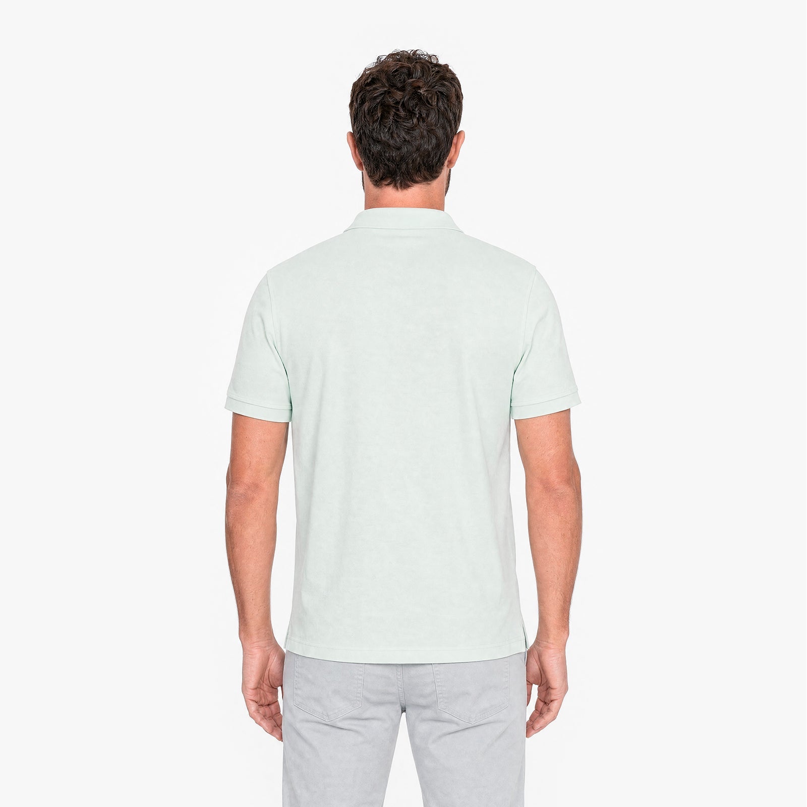 Man wearing a light green polo shirt on a white background