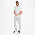 Man wearing a light green shirt and gray pants on a white background