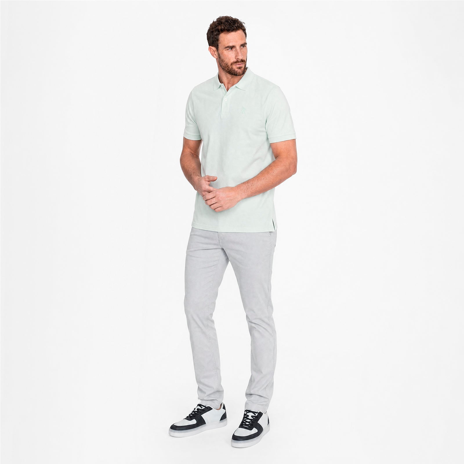 Man wearing a light green shirt and gray pants on a white background
