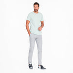 Man wearing a light green t-shirt and gray pants on a white background