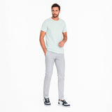 Man wearing a light green t-shirt and gray pants on a white background