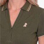 Close-up of a green polo with an embroidered beige dog logo