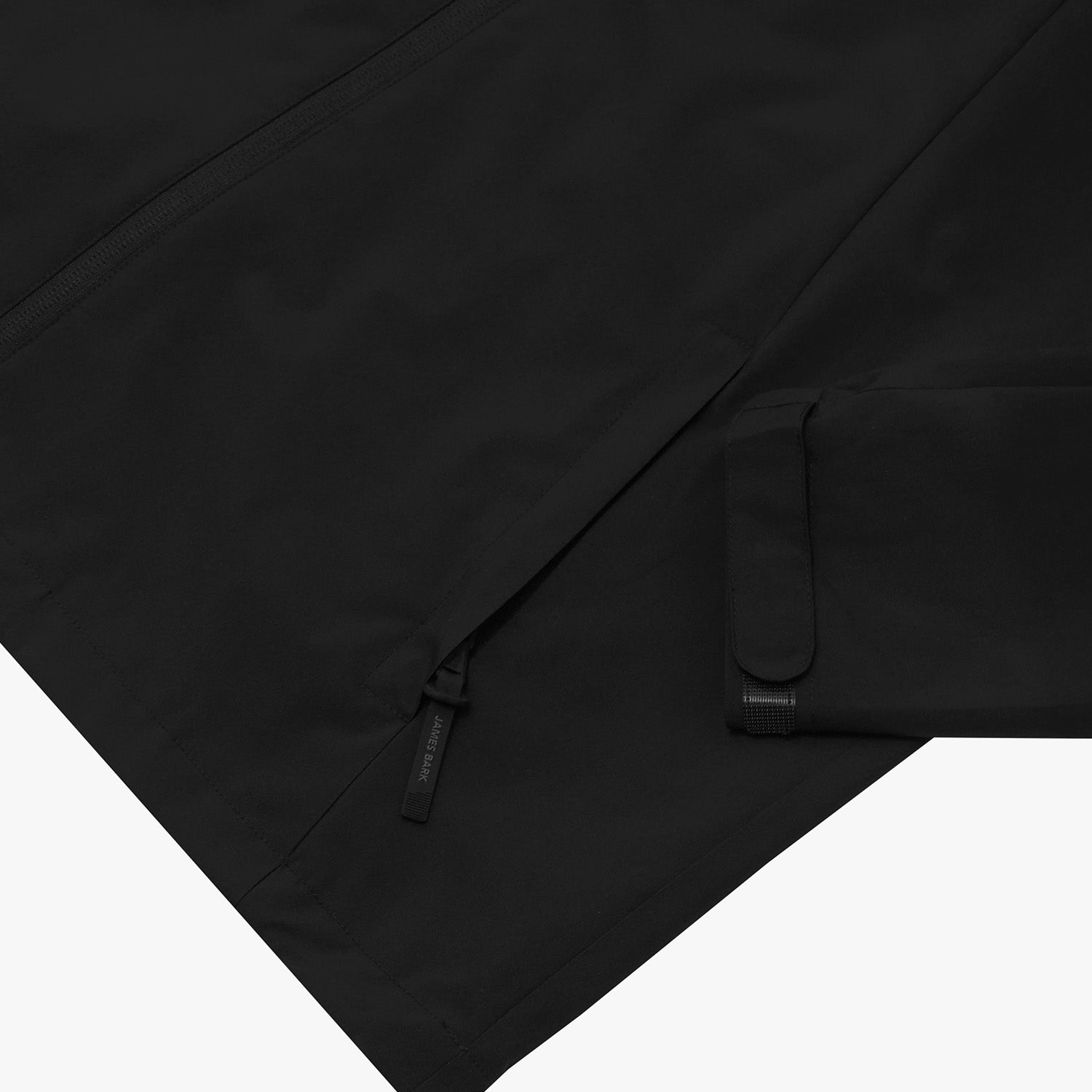 Close-up of the lower pocket and sleeve cuff of a black jacket.
