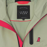 Close-up of the inside of a sage green jacket. A black label reads "SPECIAL EDITION JAMES BARK." The lining is bright pink.