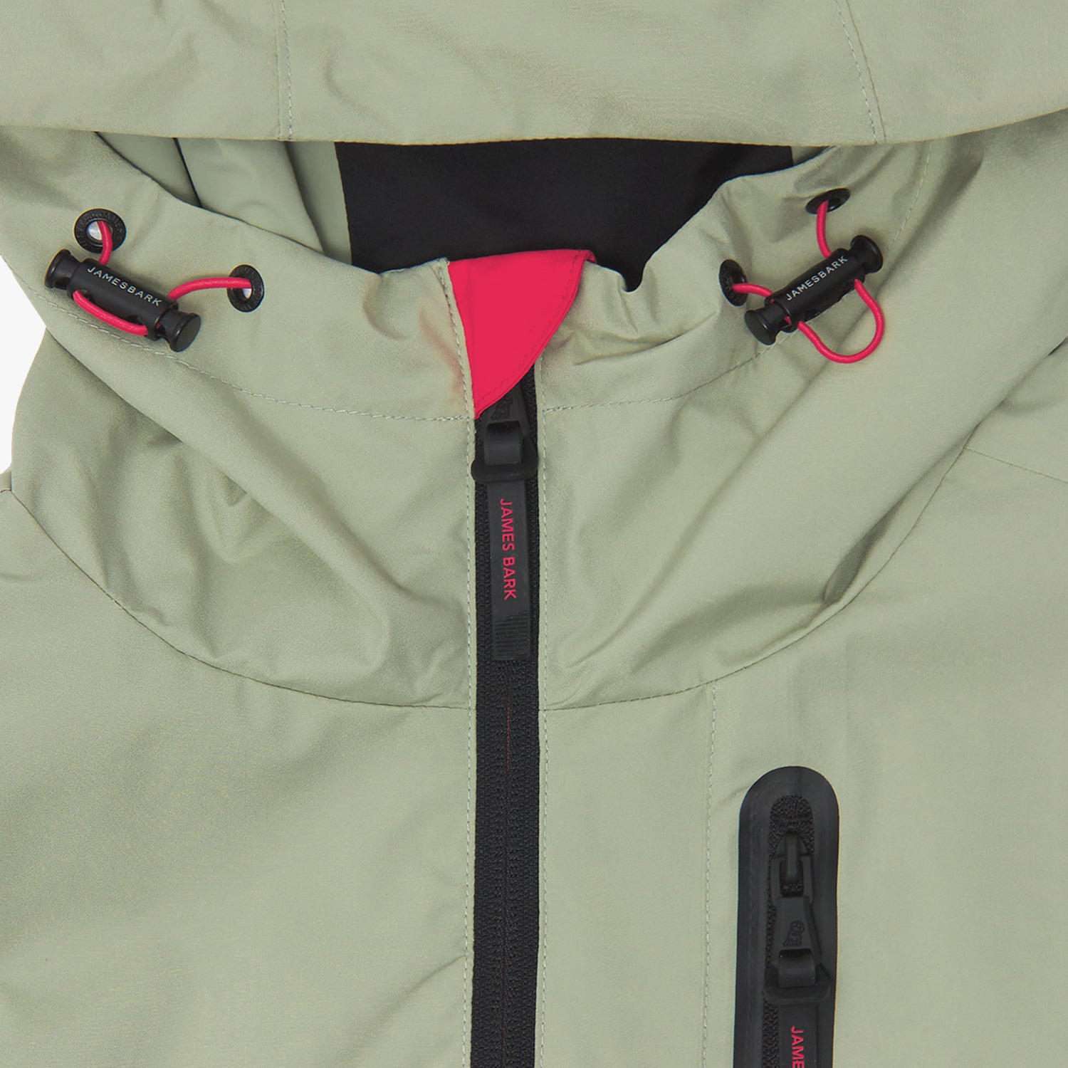 Close-up of the hood and upper chest of a sage green jacket. The hood has black toggles with red accents.