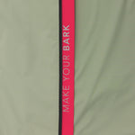 Close-up of the sleeve of a sage green jacket. A vertical pink stripe with the words "MAKE YOUR BARK" runs down the sleeve.