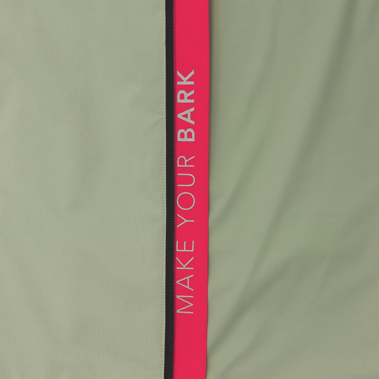 Close-up of the sleeve of a sage green jacket. A vertical pink stripe with the words "MAKE YOUR BARK" runs down the sleeve.