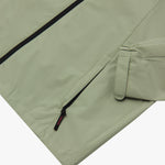 Close-up of the lower pocket and sleeve cuff of a sage green jacket. 