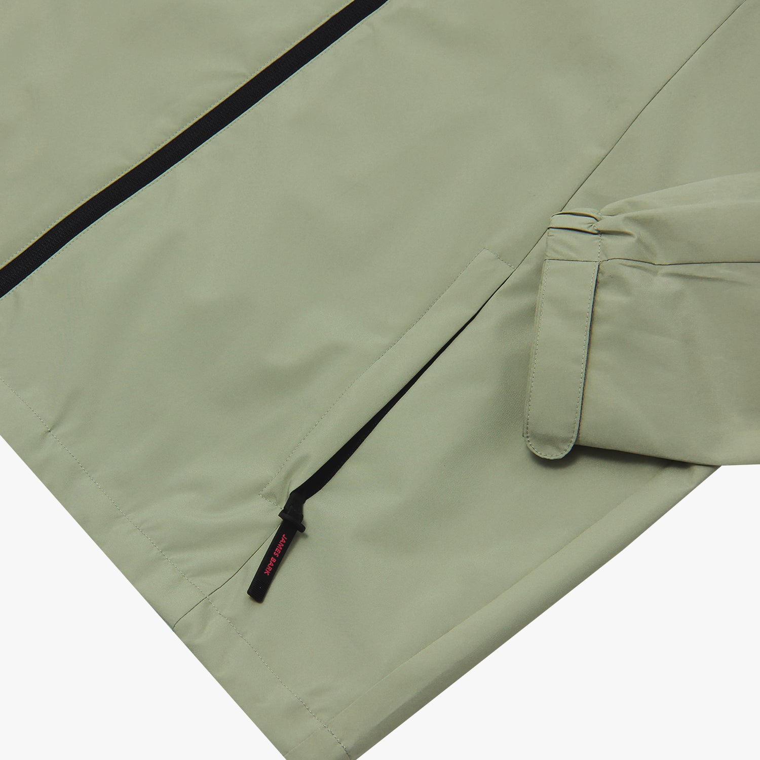 Close-up of the lower pocket and sleeve cuff of a sage green jacket. 