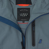 Close-up of the inside of a slate blue jacket. A black label reads "SPECIAL EDITION JAMES BARK". The lining is burnt orange.