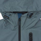 Close-up of the hood and upper chest of a slate blue jacket. The hood has black toggles with blue accents. 