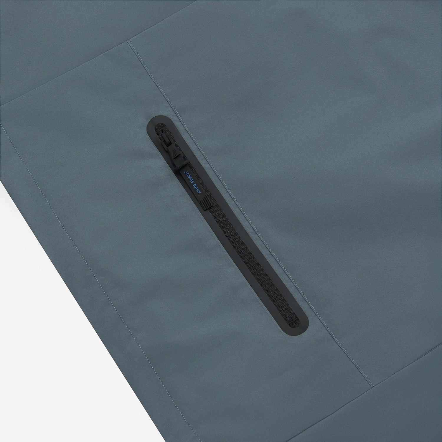 Close-up of the chest pocket of a slate blue jacket.