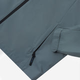 Close-up of the lower pocket and sleeve cuff of a slate blue jacket. 