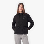 A woman modeling a black lightweight zip-up jacket with a small white logo on the left chest