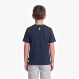 A child viewed from the back wearing a navy blue short-sleeve t-shirt with a small white dog logo on the upper back, paired with light gray pants, against a plain white background.