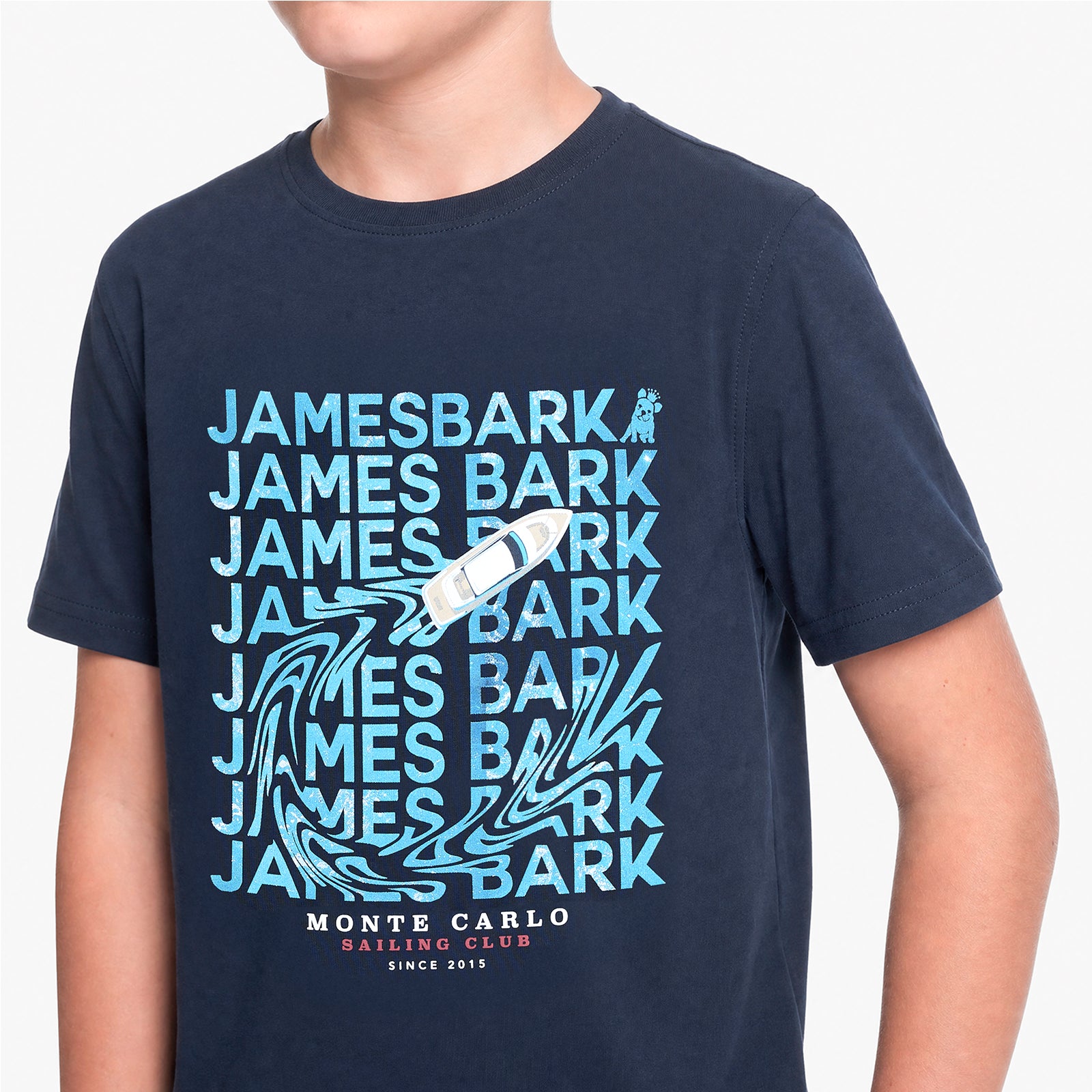 A navy blue short-sleeve t-shirt with a light blue and white graphic print featuring the text 'JAMES BARK' repeated, a sailboat, and 'MONTE CARLO SAILING CLUB SINCE 1915'.