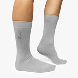 Gray socks with a small logo on the leg worn by a person on a white background