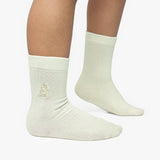 Beige socks with a small logo worn by a person on a white background